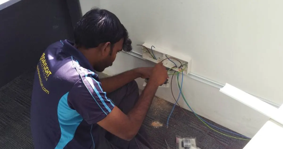 Daylight Electrician technician wiring a wall socket