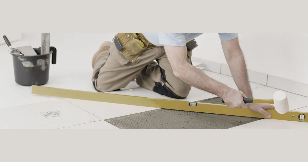 Tiler laying floor tiles with a spirit level
